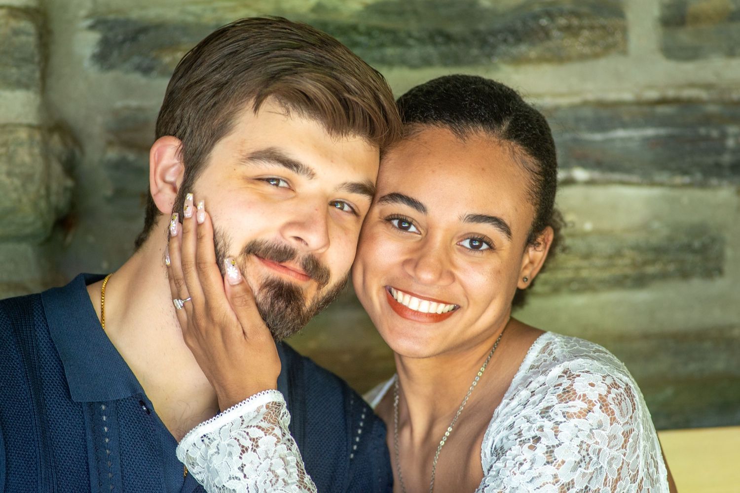 A couple in wedding attire share an intimate moment against a rustic wooden wall background.