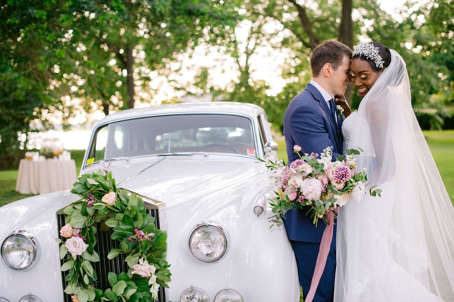 Vintage white Rolls Royce car adorned with floral decorations serves as an elegant wedding day transportation.