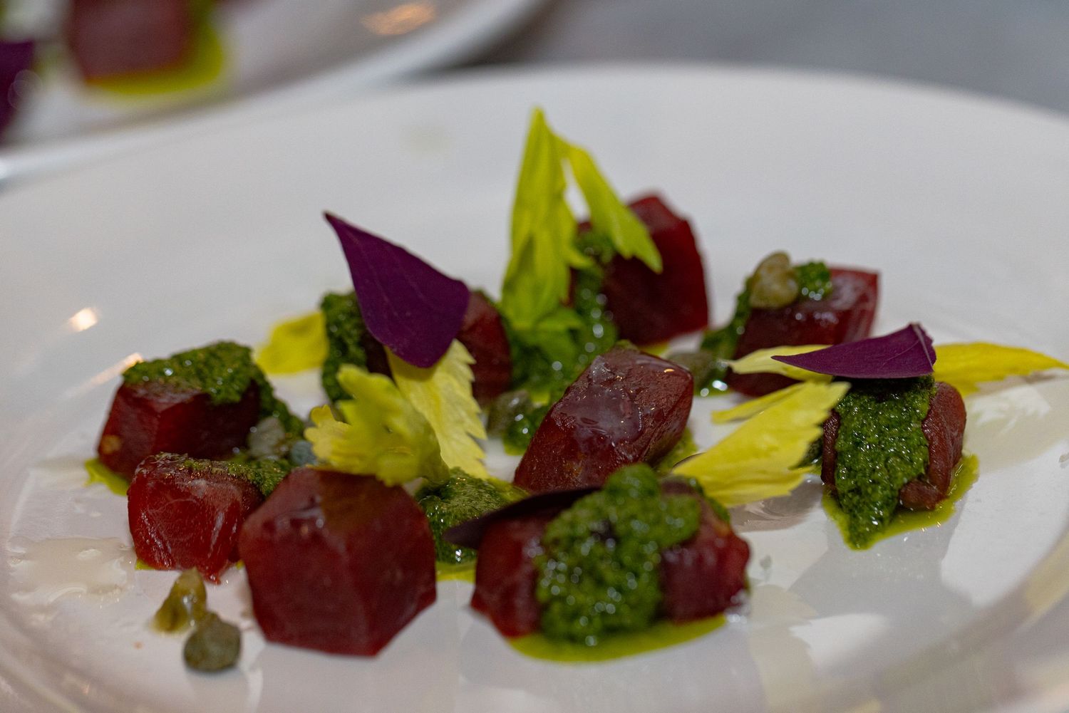 Elegant plated appetizer with roasted beets, broccoli and microgreens arranged in a modern presentation.