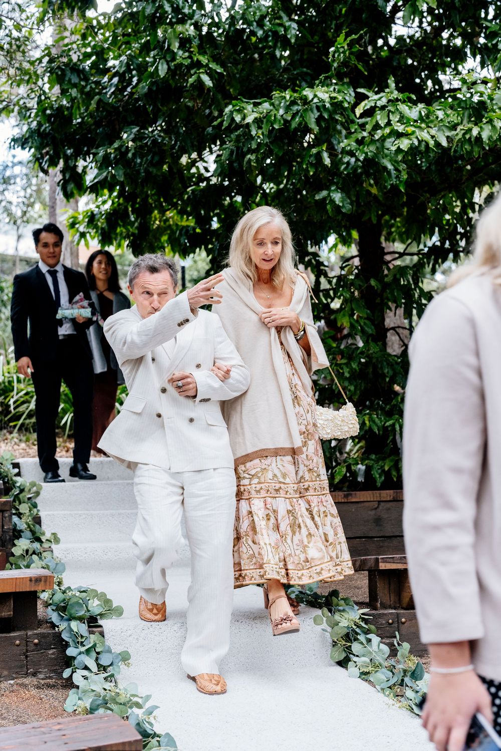 A sequence of four photos showing people dancing at an outdoor wedding reception under green trees.
