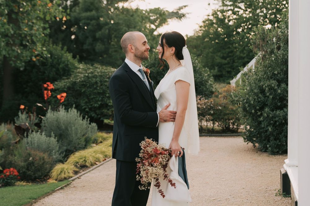 A couple shares a romantic moment in the lush Langtons House garden setting during their wedding celebration.