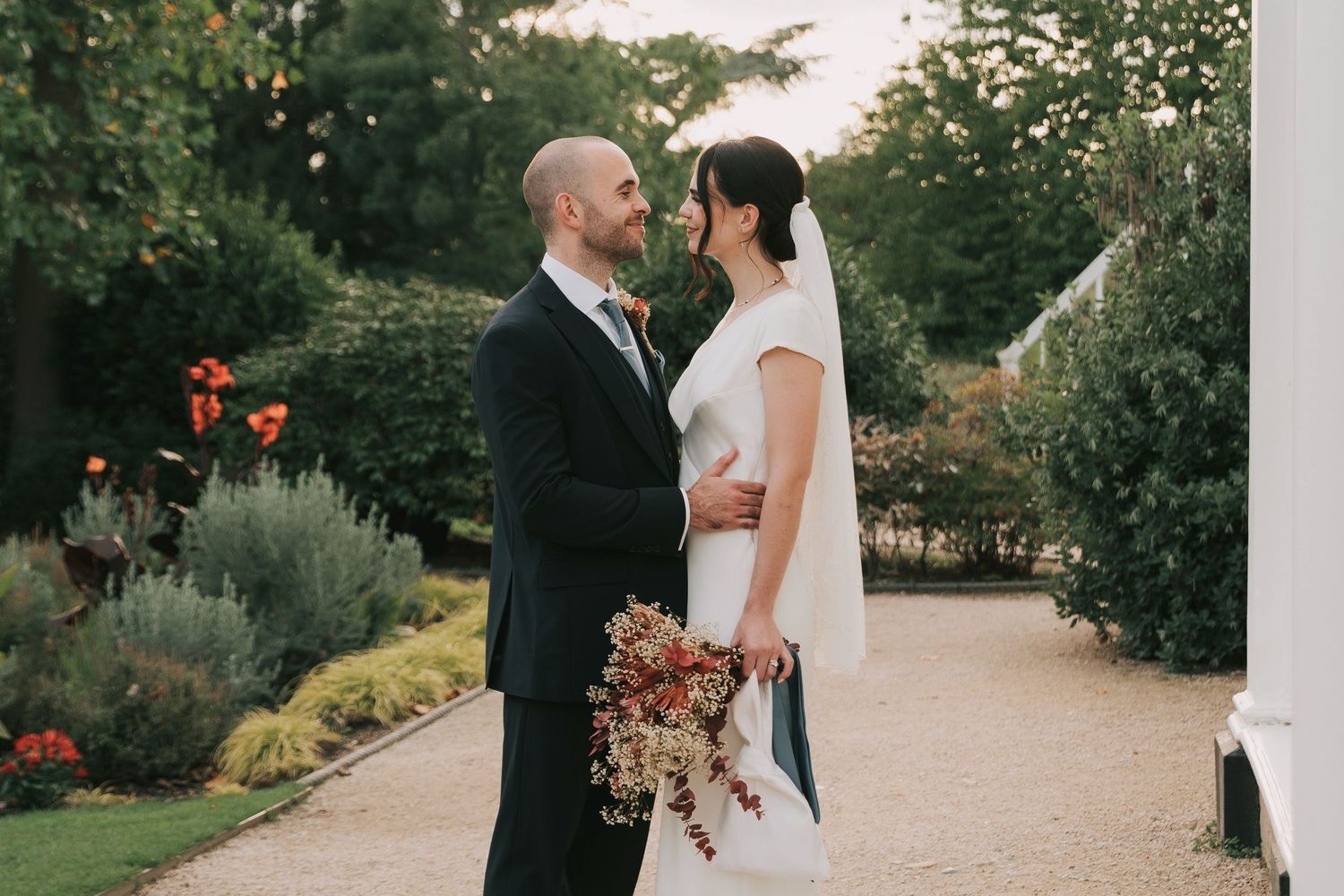 A couple shares a romantic moment in a lush garden setting during their wedding celebration.