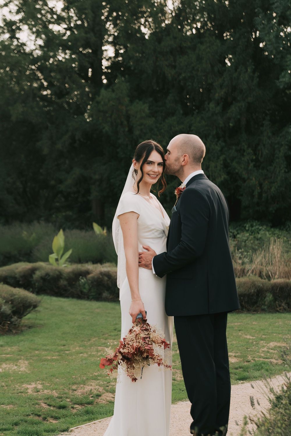 A couple shares an intimate moment during their outdoor wedding ceremony surrounded by lush greenery.