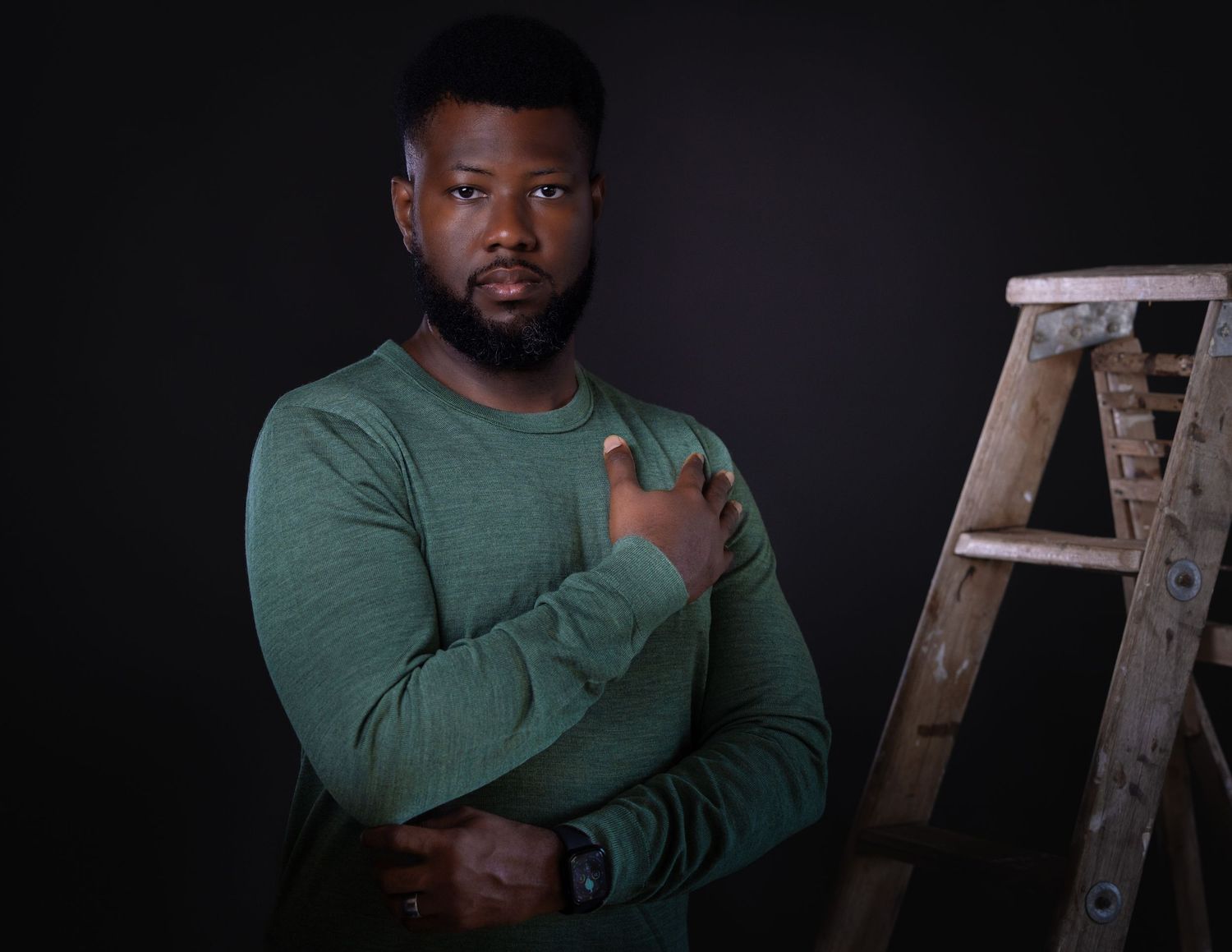 A person wearing a green sweater stands against a dark background in a series of progressive poses.