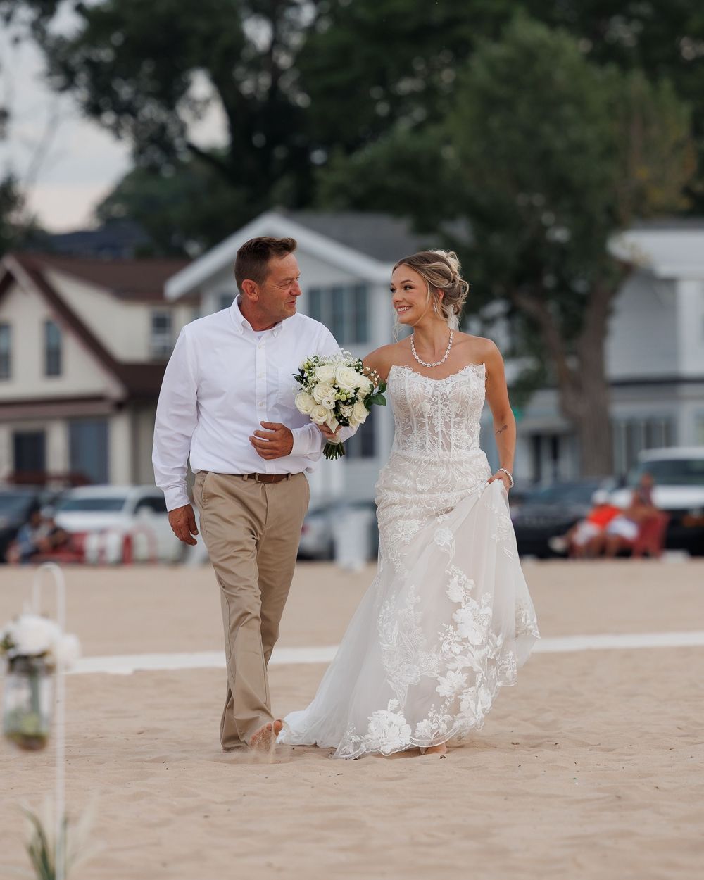 A couple walks together on a sandy beach during their wedding celebration.