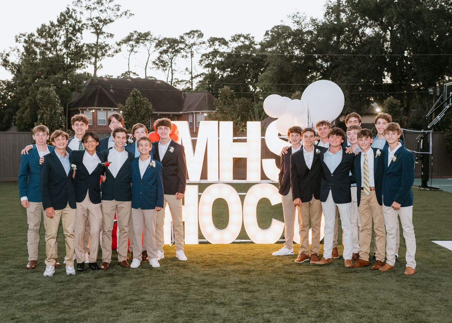A group wearing matching navy jackets and khaki pants poses together outdoors for a formal photo session.