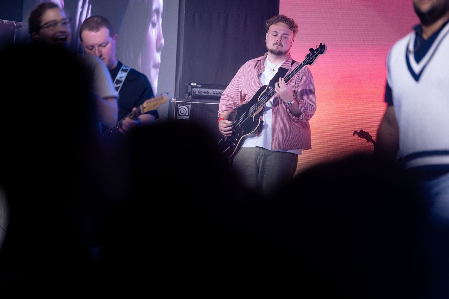 Musicians perform on stage with colorful lighting and instruments during a live concert performance.