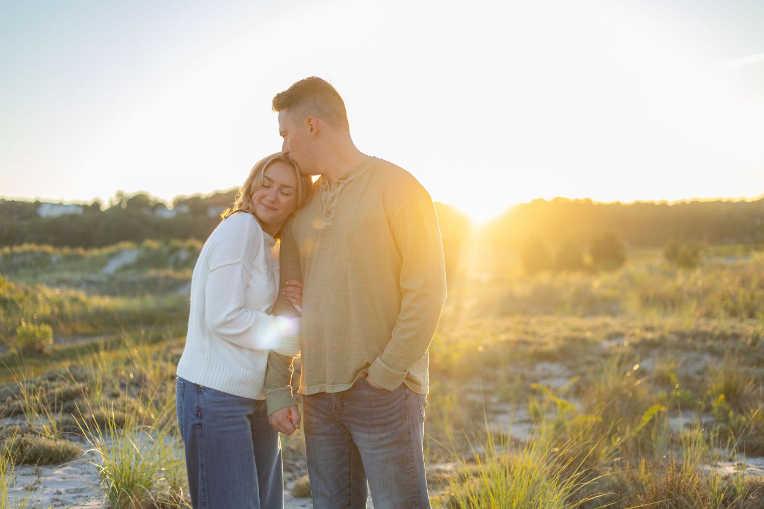 A romantic engagement photo session in a golden marsh field during sunset.