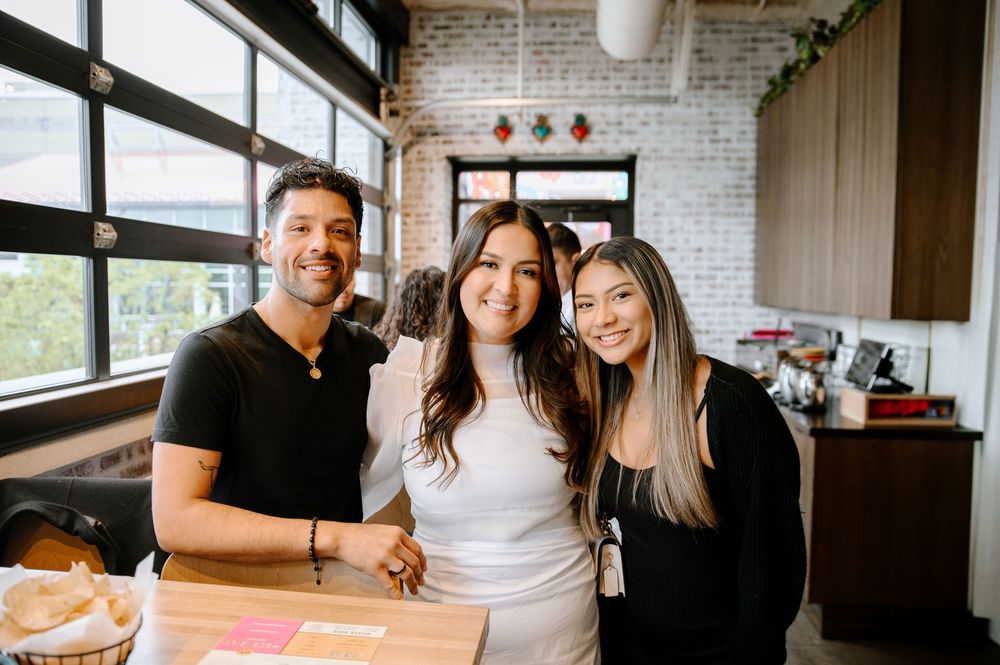 Group of friends gather in modern kitchen with white brick walls and dark wood cabinets for casual social time.