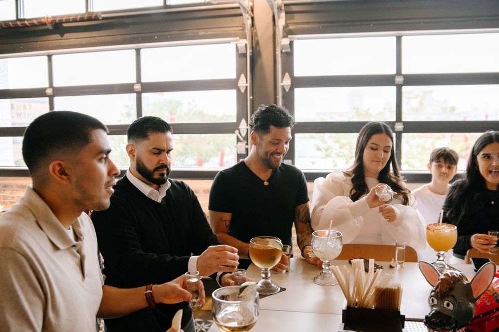 A group of people sit at a table tasting coffee and taking notes during a professional cupping session.