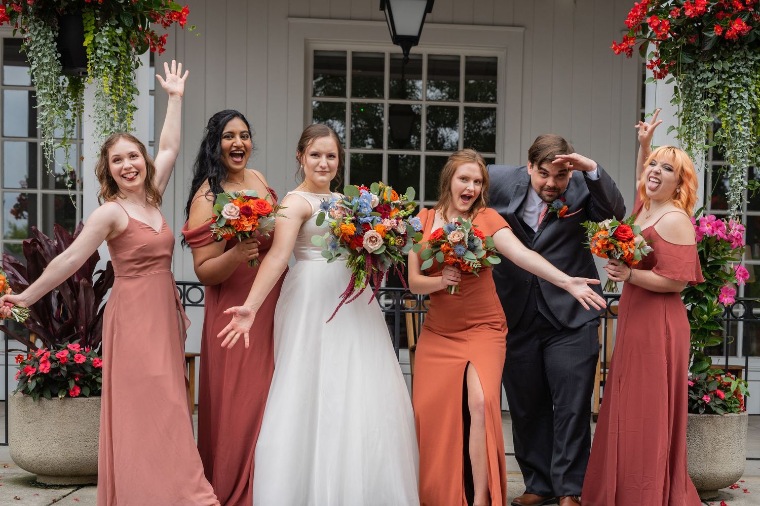Columbus Ohio Wedding Venues party in coral bridesmaid dresses poses in front of a flower-covered building.