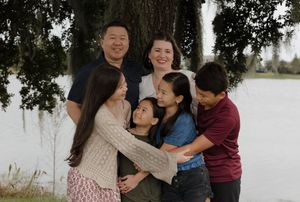 A group shares warm embraces while standing by a lakeside.