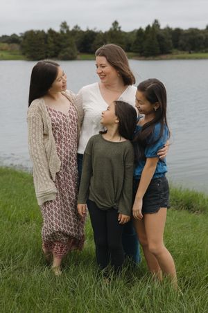 A group stands together in casual attire near a lake with tall grass in the foreground.