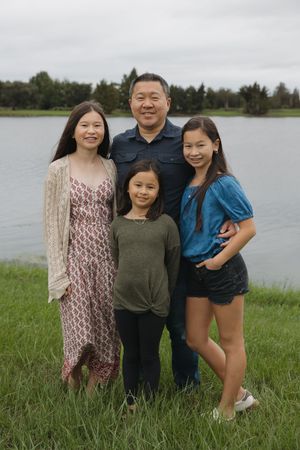 A family group poses together on grassy shoreline with a lake in the background.