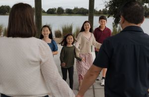 A group of people in casual attire interact and smile together outdoors.