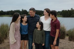 A group enjoys a casual outdoor photoshoot by the water on a cloudy day.