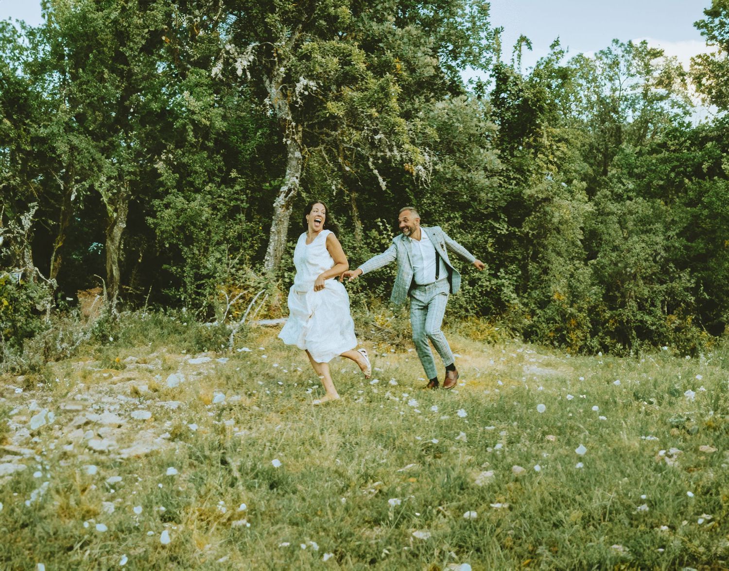 Couple running joyfully in nature during romantic outdoor wedding photography session. Segovia Spain.