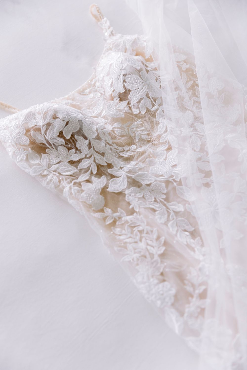 Delicate lace detail of white wedding dress fabric in close-up macro photography.