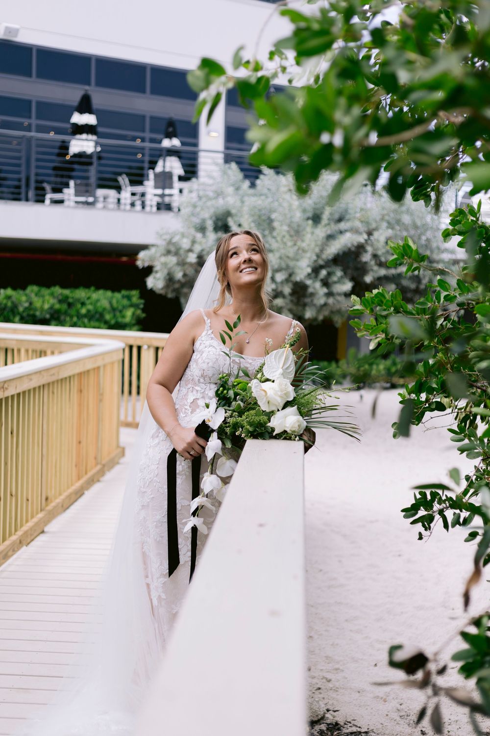 A white wedding dress is photographed on a wooden boardwalk deck overlooking the water.