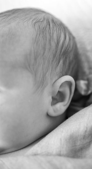 Close-up black and white image of a sleeping baby's head resting on soft fabric.