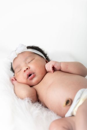 A sleeping newborn baby lies peacefully on soft white bedding in a series of connected artistic photos.