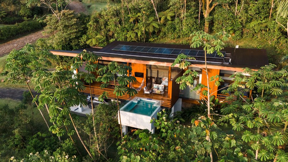 Panoramic view of eco-friendly villa with wooden deck integrated into tropical landscape.