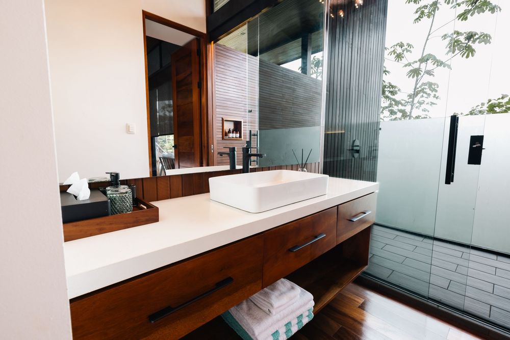 Modern bathroom with white tiles, wooden accents, and large mirror reflecting natural light.