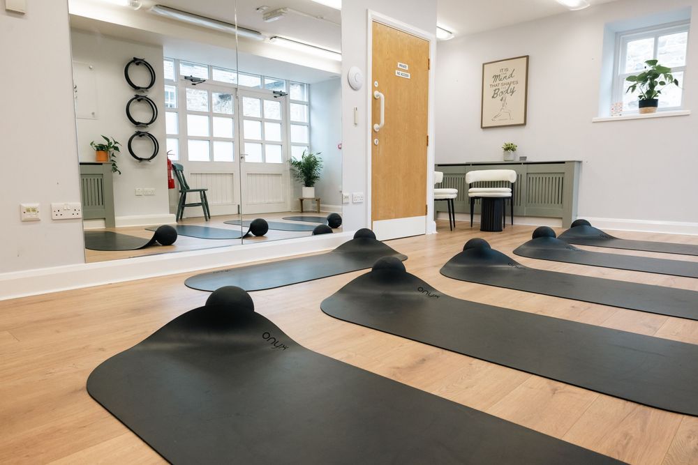 Clean, minimalist pilates studio interior with wood floors and exercise mats.