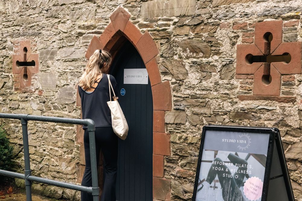 Stone archway entrance with black door and decorative cross details.
