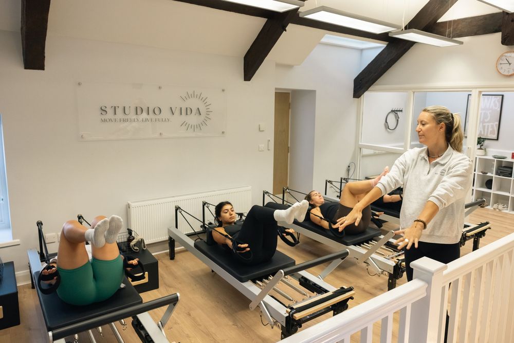 Bright pilates studio interior with wooden beams and exercise equipment.