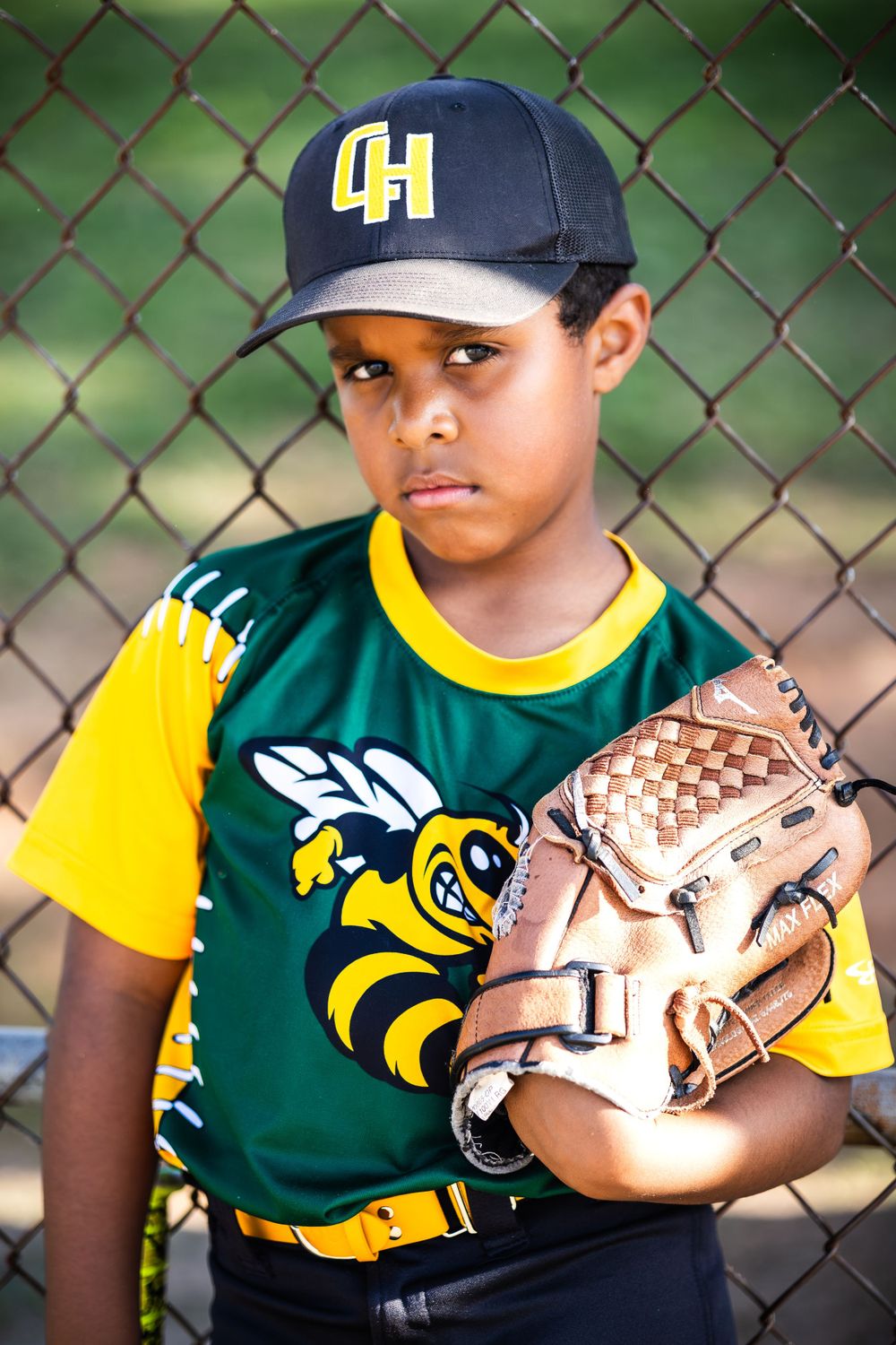 Youth baseball player wearing a green and yellow uniform with 4H cap and baseball glove.