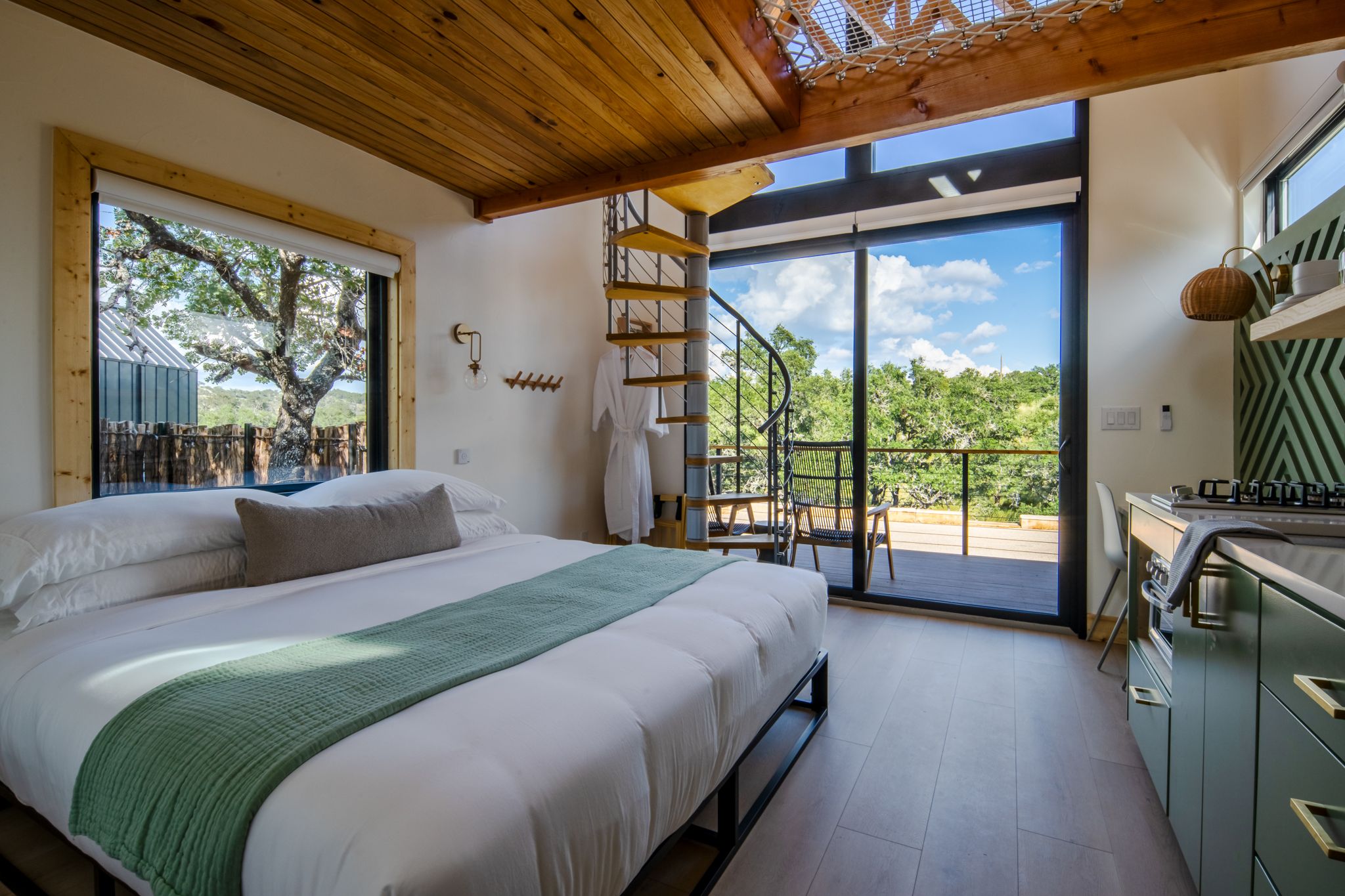 Luxurious tiny home interior featuring a bed with mountain views through floor-to-ceiling windows.