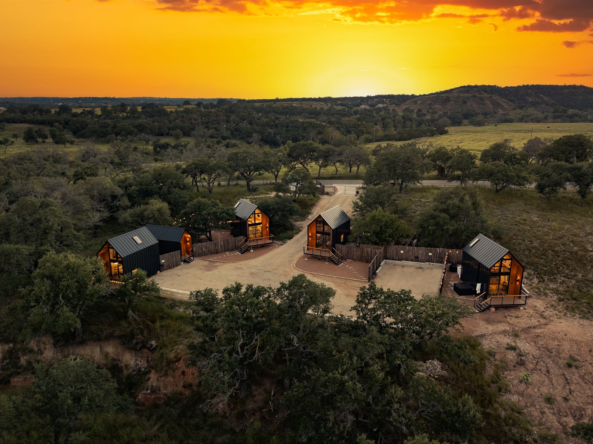Aerial view of luxury cabin rentals arranged in a circle during a vibrant orange sunset.