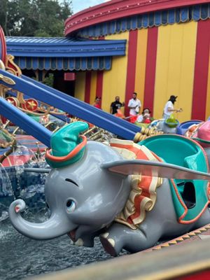 Closeup view of gray whale sculptures adorning a carnival or theme park ride with colorful blue and red details.