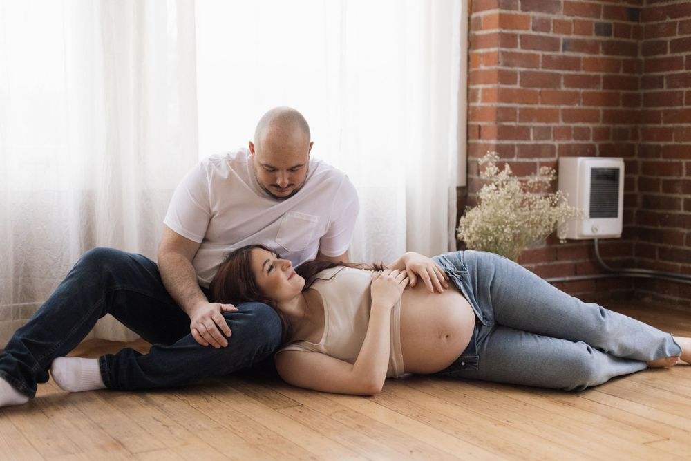 Couple sitting on hardwood floor of brick wall room sharing intimate moment together.