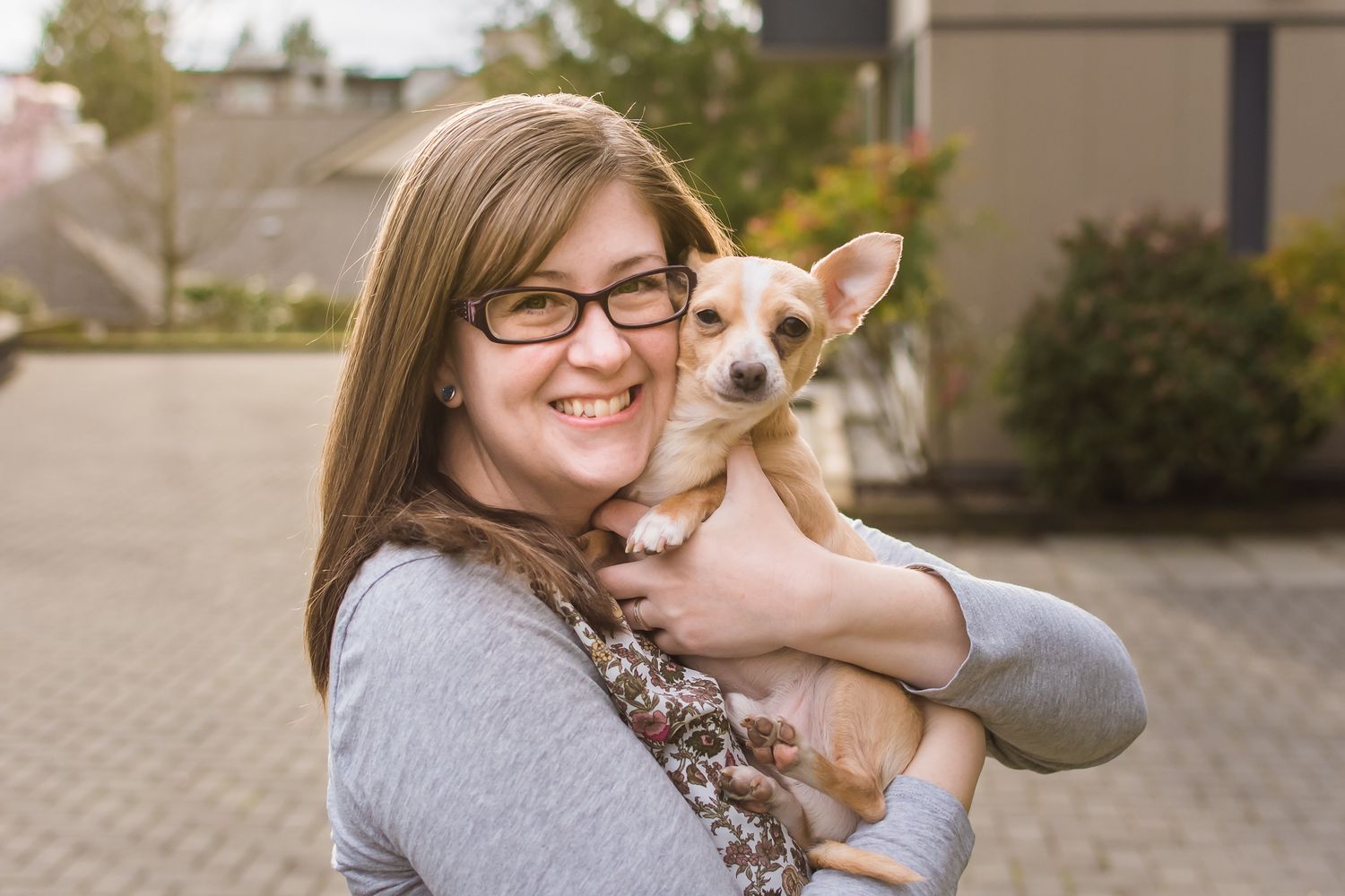 A photo of Kari Mills (photography) hugging her dog, Dusty, close as she smiles at the camera. Maple Ridge, BC.