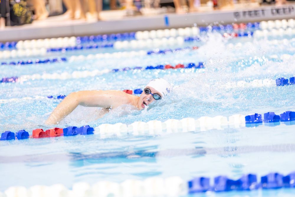 Swimmers racing in a competitive swimming pool with blue lane dividers during a swim meet competition.