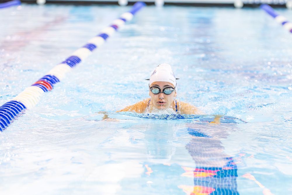 Swimmers practicing laps in a pool with lane dividers marked by red and blue stripes.