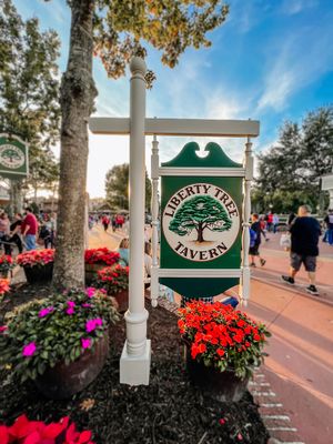 Decorative green sign post with Pineview logo surrounded by vibrant red and purple flowers at a Disney park.