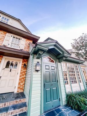 A charming historic home entrance features a sage green door with decorative trim and traditional brick facade details.