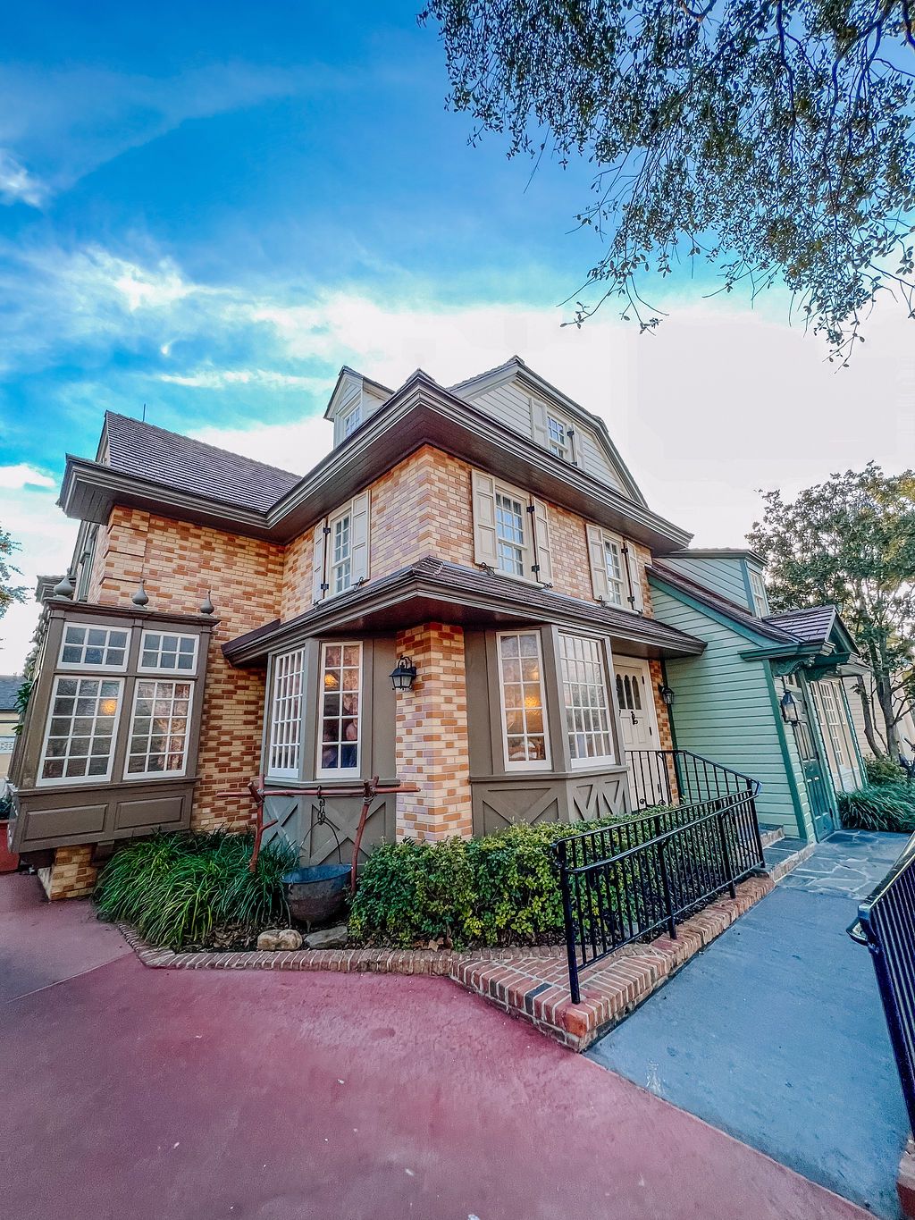 Beautiful stone and brick Victorian-style house with wrap-around porch and large windows under vibrant blue skies.