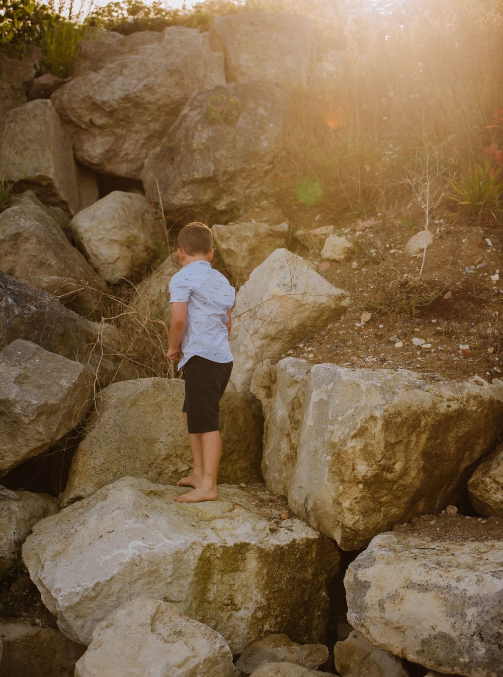 Family photoshoot in Weymouth, Dorset. A young boy is climbing rocks on a Weymouth, Beach. Weymouth photoshoot. Weymouth beach.
