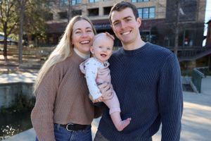 Happy family smiling together outdoors on a sunny day wearing cozy sweaters.