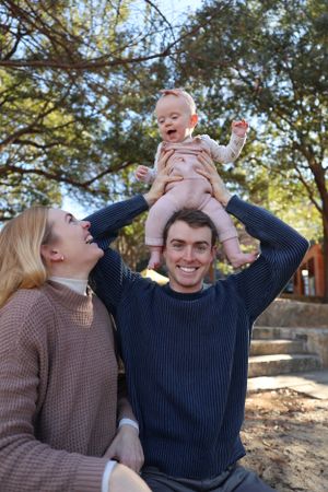 Family enjoying a playful moment together outdoors on a sunny autumn day in a knit sweaters.