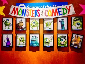A colorful display board titled 'Monsters of Comedy' showcases twelve cartoon monster photos arranged in rows.