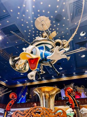 Decorative carousel ceiling with vintage Disney animations in gold and blue adorned with twinkling stars at a theme park ride.