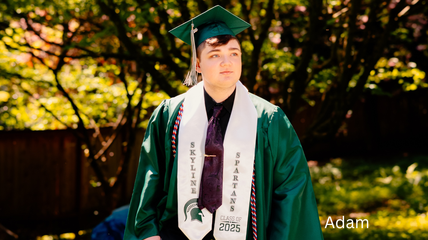 Graduate in green cap and gown with honors stole posing outdoors in golden sunlight.