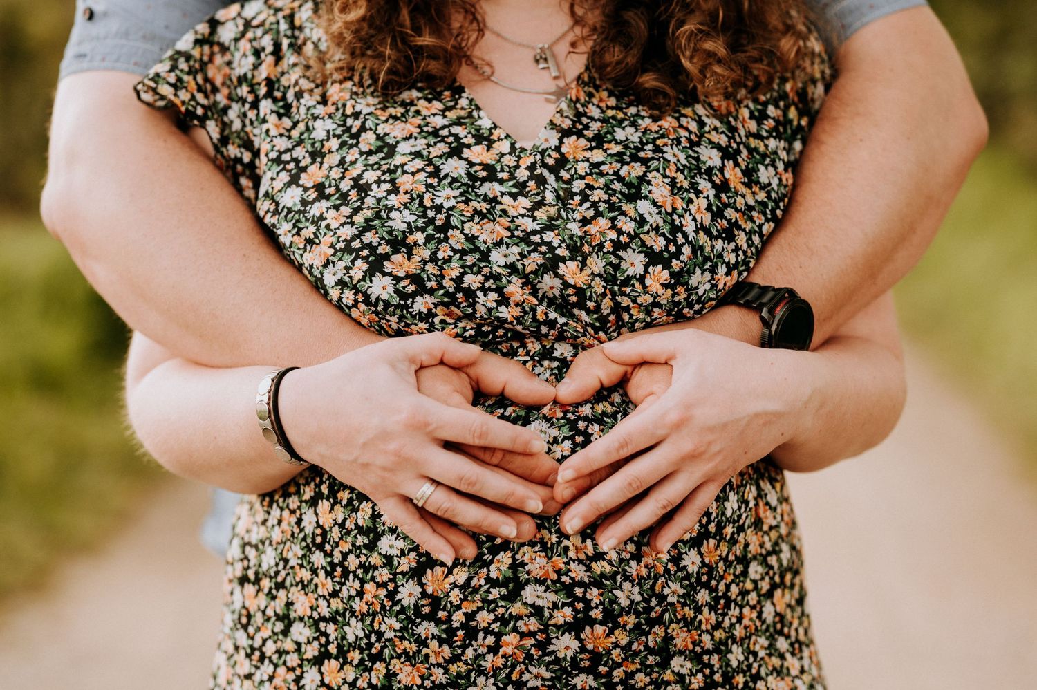 Een stel staat samen rechtop. De vrouw is zichtbaar zwanger. De handen van de man liggen op haar ronde buik.