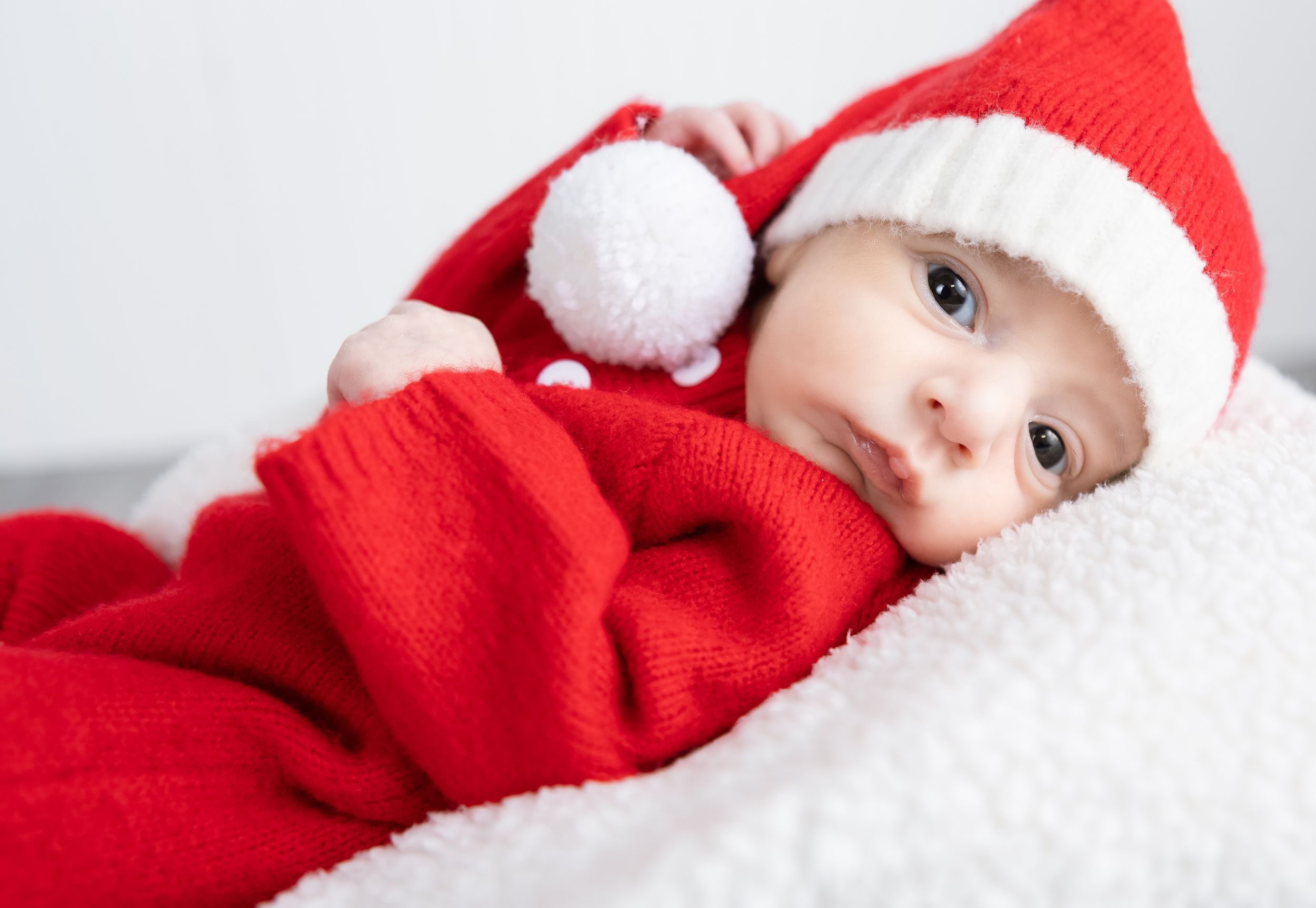 Holiday milestone photography featuring a sleeping baby in a red Santa suit in Lincoln