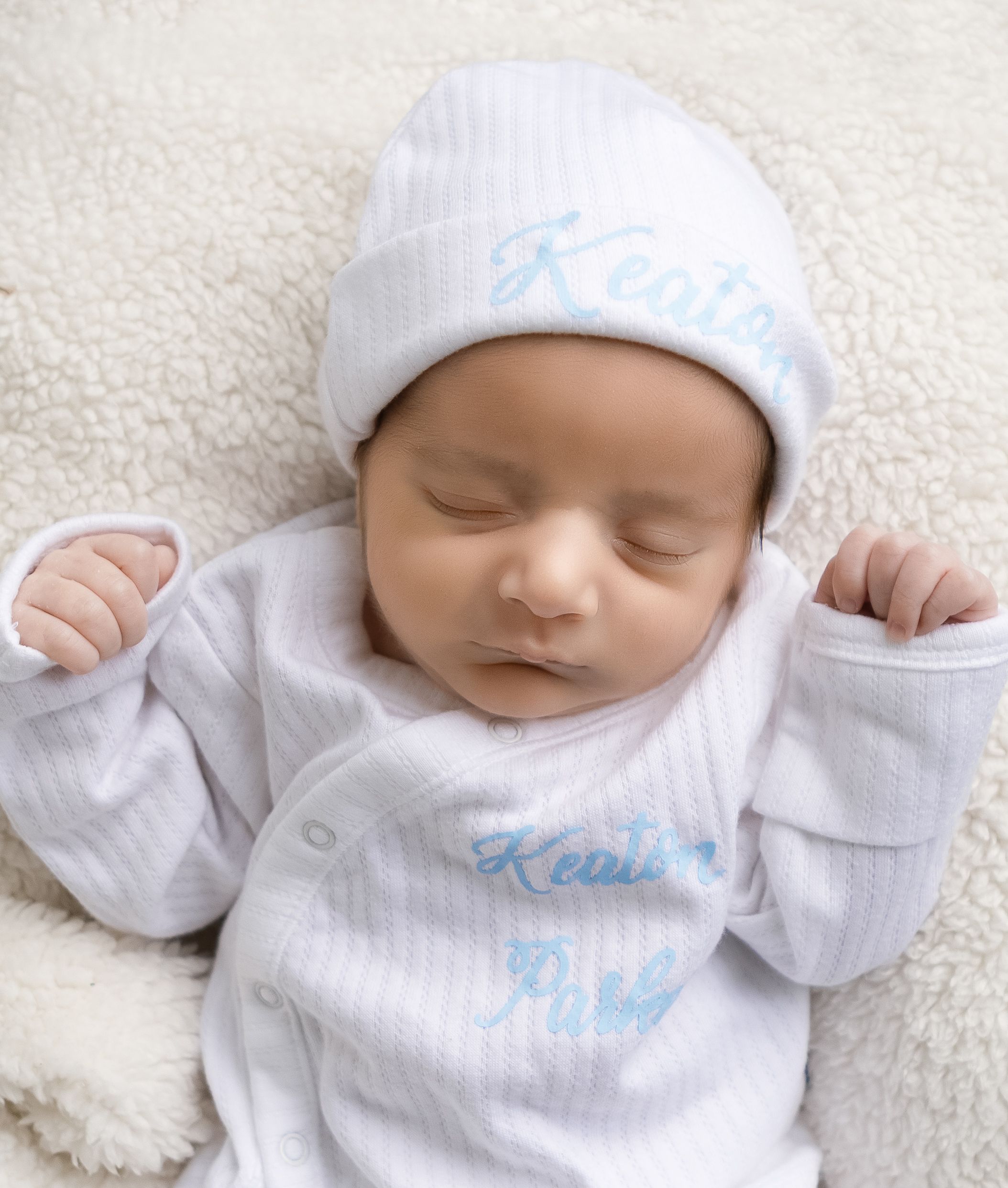 Authentic newborn portrait in Lincoln, Alabama, capturing a sleeping baby in a cozy white hat.